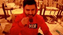 a man wearing a red pan ver hoodie drinks from a glass