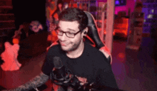 a man wearing glasses is sitting in front of a microphone in a room .