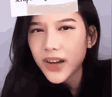 a close up of a woman 's face with a paper on her forehead .