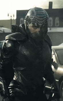 a man in a black armored suit is standing in front of a building
