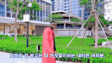 a man in a red cape is standing in front of a building in a park