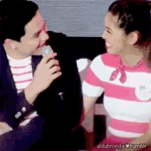 a man is holding a microphone next to a woman in a pink striped shirt