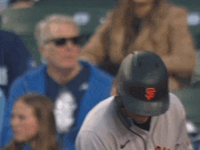 a man wearing a san francisco giants hat looks down at something