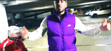 a man wearing a purple nike vest is standing in a parking lot