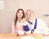 two girls are sitting at a table with bowls of food and chopsticks and one of them is eating something with chopsticks .