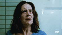 a woman is crying in front of a wall that says fx on it