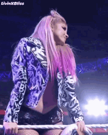 a woman with pink hair is standing on a rope in a wrestling ring