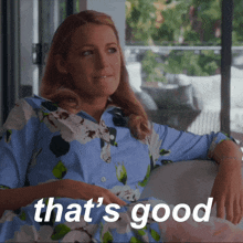 a woman in a blue floral shirt is sitting on a couch with the words that 's good written below her
