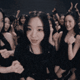a group of women in black dresses are dancing