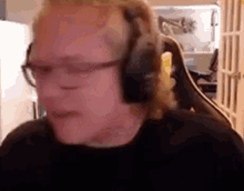 a man wearing headphones and glasses is sitting in a chair and making a funny face .