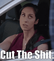 a woman is sitting in a car with the words cut the shit written below her
