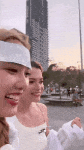 a woman with a bandage on her head is standing next to another woman