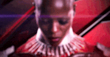 a close up of a woman 's face with a necklace around her neck and a red background .