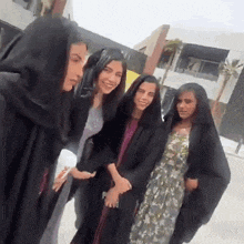 a group of women wearing abayas pose for a photo