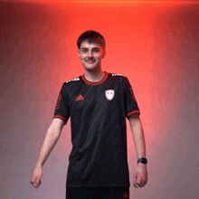 a man wearing a black adidas shirt stands in front of a red light