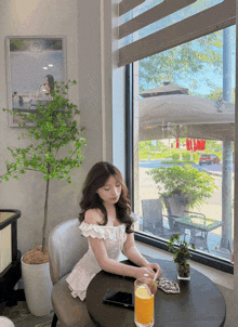 a woman sits at a table looking out a window