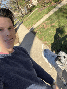 a man in a blue sweater is standing next to a dalmatian dog