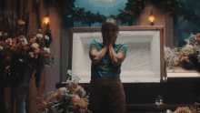 a woman is standing in front of a coffin with her hands over her face