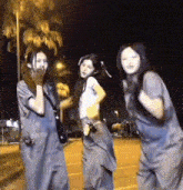 a group of three women are standing next to each other in a parking lot at night .