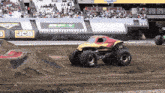 a monster truck is driving on a dirt track in front of a jcb banner
