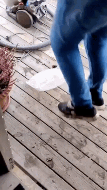 a person walking on a wooden deck with a vacuum cleaner behind them