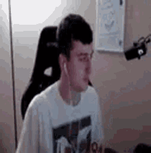 a man wearing headphones is sitting in a chair in front of a microphone in a room .