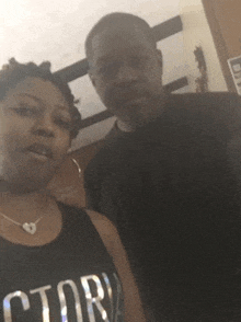 a man and a woman are posing for a picture and the woman is wearing a black tank top that says ctor