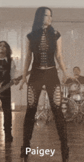 a woman with blue hair is standing in front of a drum set and the name paigey is on the bottom