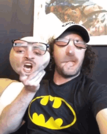 a man wearing glasses and a batman shirt makes a face
