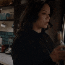 a woman in a black shirt is holding a bottle of alcohol