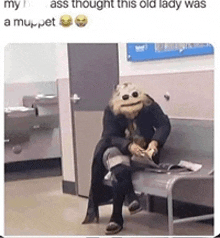 a woman wearing a muppet mask is sitting on a bench in a hospital waiting room .