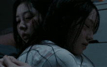 two women are hugging each other in the dark and one has a bloody face