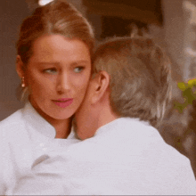 a man kisses a woman on the cheek while she looks at him