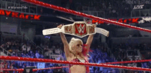 a woman is holding a wrestling championship belt over her head