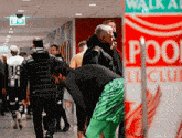 a group of people walking in a hallway with a sign that says walk all pool club