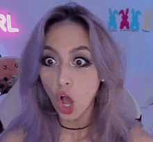 a woman with purple hair is making a funny face in front of a neon sign that says rl .