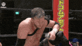 a man is wrestling another man in a wrestling ring with a sign in the background that says ' a ' on it