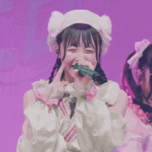 a girl in a white hat is singing into a green microphone