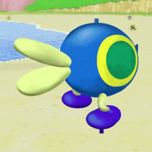 a blue ball with a yellow circle in the middle is walking on a beach