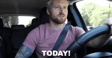 a man in a pink shirt is driving a car and the word today is on the steering wheel