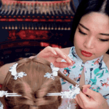 a woman in a floral dress is styling a child 's hair .