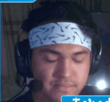 a man wearing headphones and a headband with a blue t on it