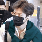 a man wearing a black face mask and a green sweater