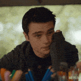 a man sitting at a table with a bunch of pencils and a netflix logo on the bottom right