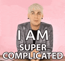 a man in a silver jacket says i am super complicated on a pink background