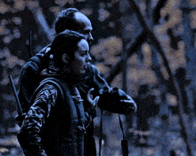 a man and a woman looking through binoculars in a dark forest