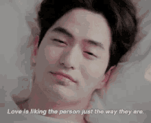 a man is laying in bed with a quote about love .