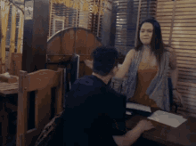 a man is sitting at a table with a woman standing next to him