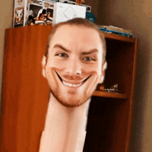 a man with a very long neck is smiling in front of a bookshelf .