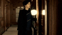 a man in a black suit is standing in a hallway
